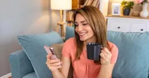 Home 22 Profissional sorridente usando smartphone para demonstrar mensagens de saudação WhatsApp eficazes para atendimento ao cliente empresarial.